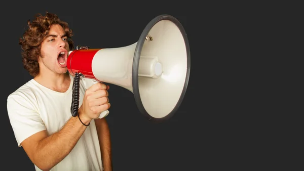 Portret van een knappe jongeman schreeuwen met megafoon — Stockfoto