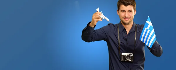 Homem segurando um avião em miniatura e bandeira da Grécia — Fotografia de Stock