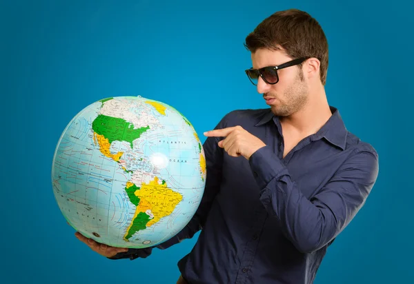 Un jeune homme pointant du doigt un globe — Photo