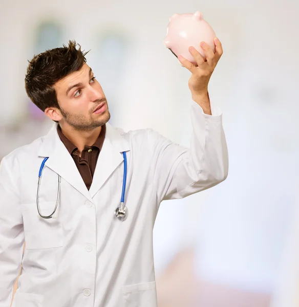 Retrato de un médico sosteniendo Piggybank — Foto de Stock