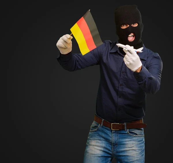 Mann trägt Räubermaske und hält Flugzeugminiatur und Fla — Stockfoto