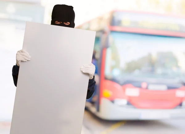 Porträtt av en man som bär mask hålla tomt kort — Stockfoto