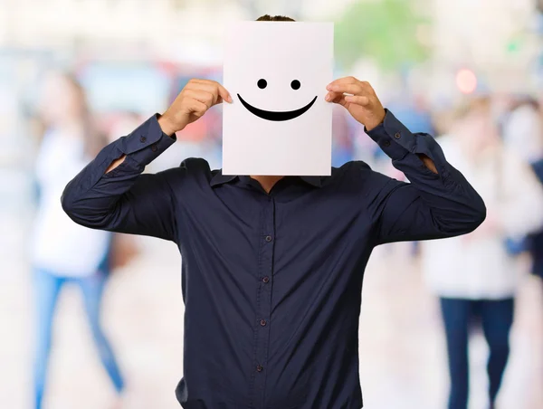 Homem segurando um cartão com papel facial — Fotografia de Stock