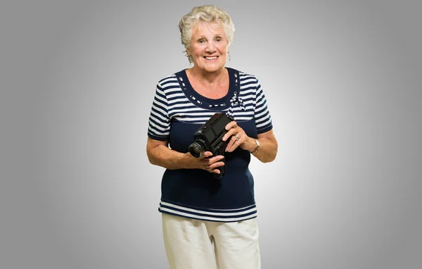 Äldre kvinna stående med videokamera — Stockfoto