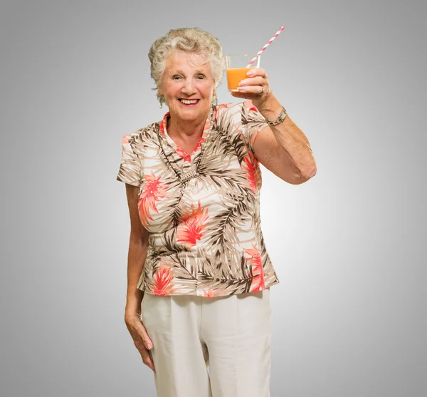 Donna anziana che tiene il vetro del succo d'arancia — Foto Stock