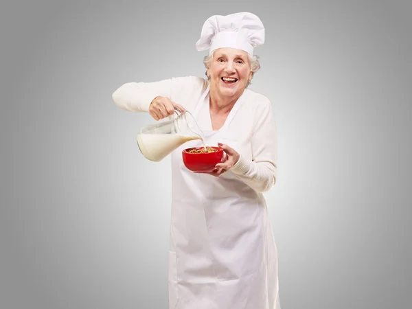 Starszy kobieta wlewając mleko — Zdjęcie stockowe