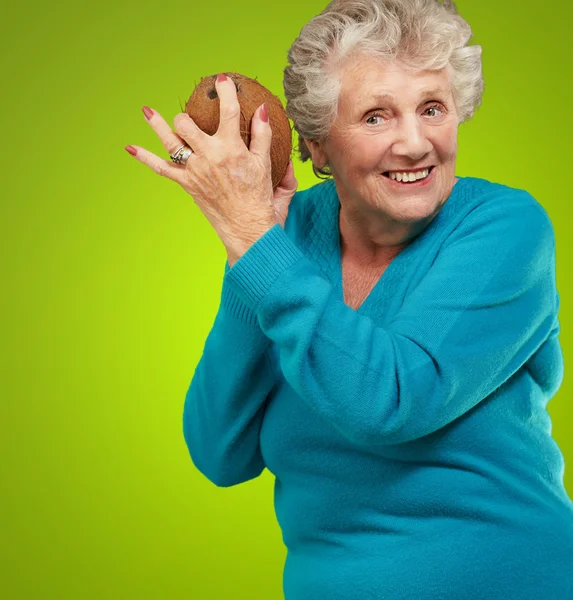 Senior happy woman holding coconut — Stock Photo, Image