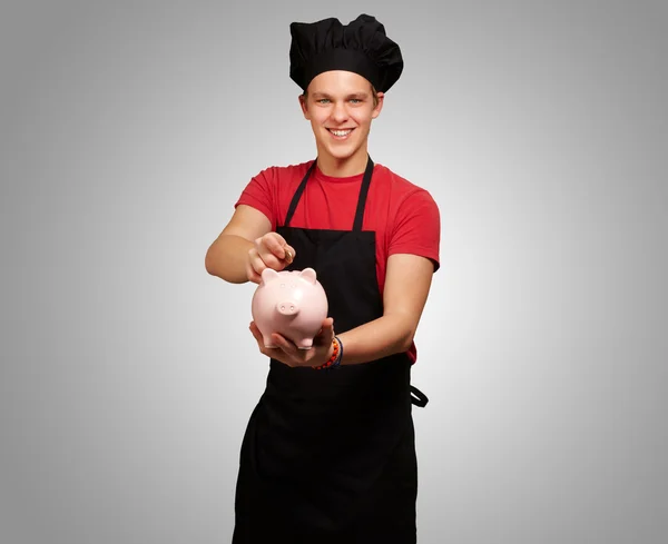 Chef con in mano un salvadanaio e una moneta — Foto Stock