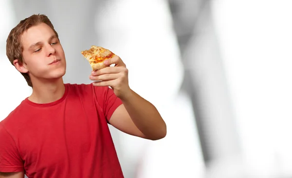 Portrait d'un jeune homme mangeant une pizza — Photo