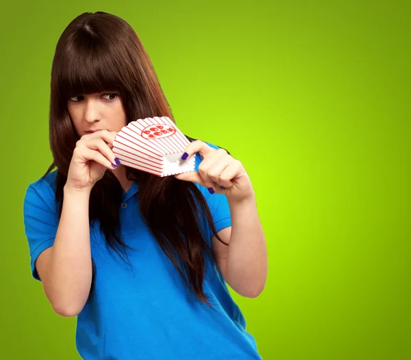 Girl looking through empty popcorn packet — Stock Photo, Image