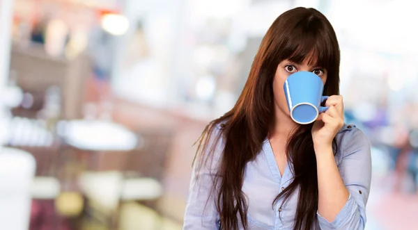 Una joven sosteniendo y bebiendo de una taza — Foto de Stock