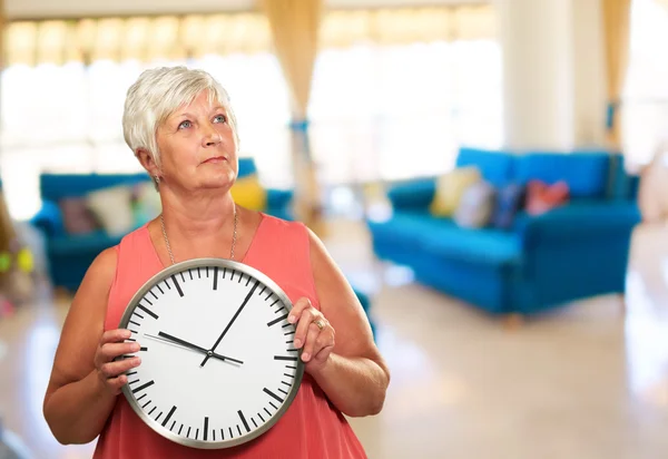 Mujer mayor sosteniendo un reloj — Foto de Stock