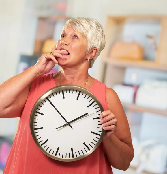 Femme âgée tenant une horloge et pensant — Photo