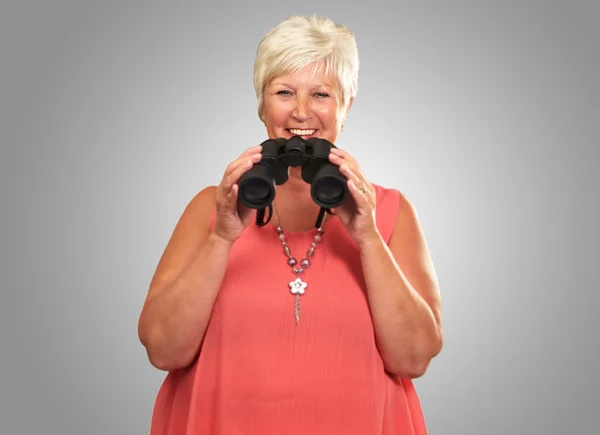 Uma mulher sênior segurando binóculos — Fotografia de Stock