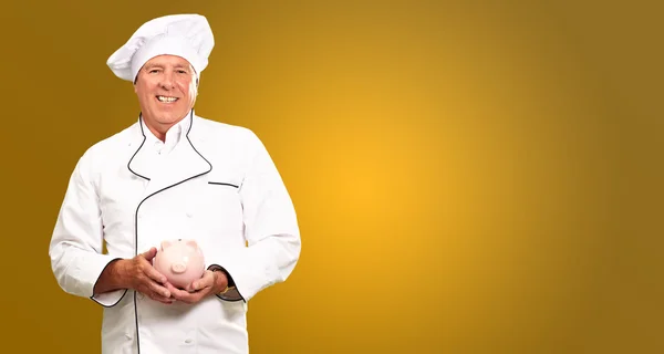Portret van een chef-kok houden piggy bank — Stockfoto