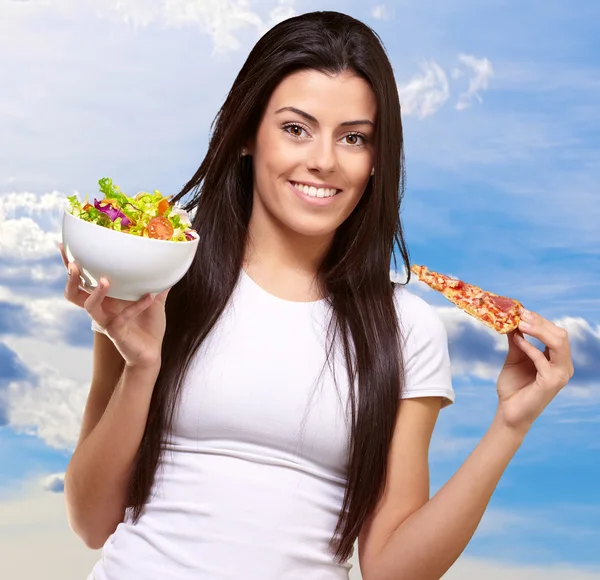 Weibchen mit einem Stück Pizza und Salatschüssel — Stockfoto
