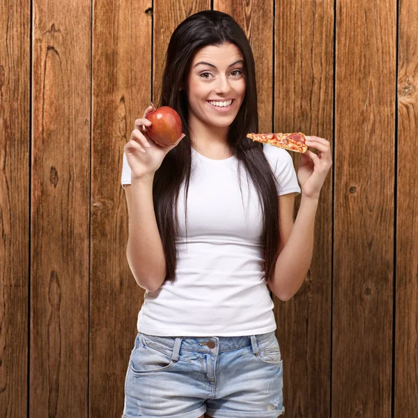 Donna che tiene un pezzo di pizza e una mela — Foto Stock