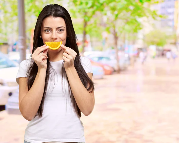 Mladá dívka drží kousek pomeranče — Stock fotografie