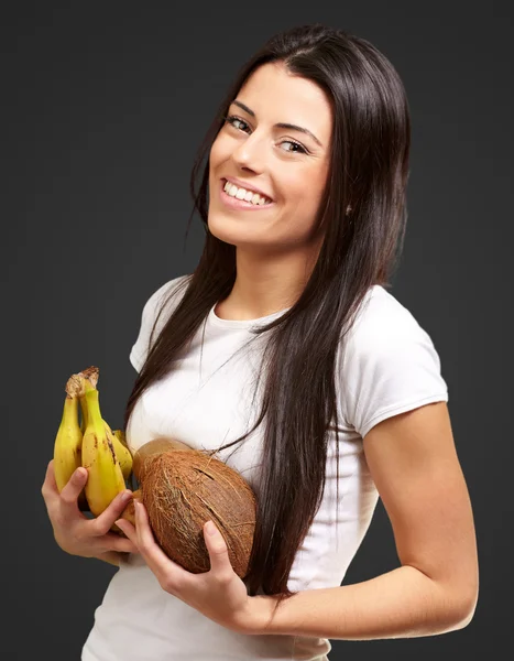 Menina segurando banana e coco — Fotografia de Stock