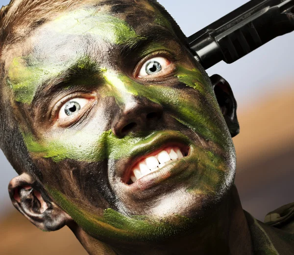 Portrait of young soldier comiting suicide against a desert Royalty Free Stock Images
