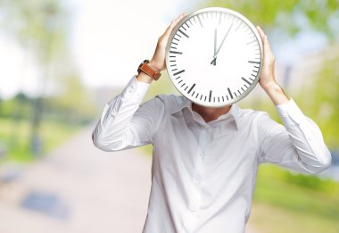 genç adam yüzünü kaplayan büyük saat tutan