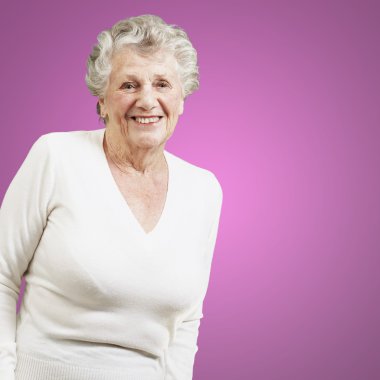 pretty senior woman smiling against a pink background