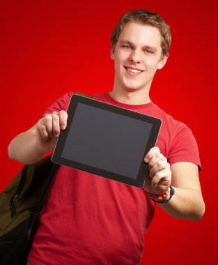 Dijital tablet kırmızı backgrou tutan genç adam portresi