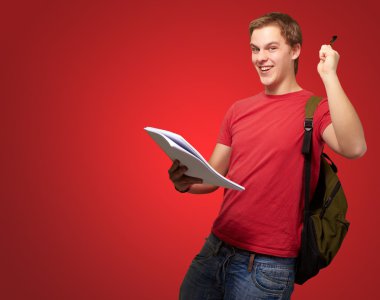 defter ve kalem kırmızı üzerinde tutarak yakışıklı öğrenci portresi