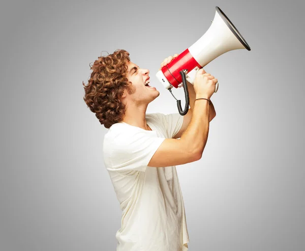 Genç adam bir megafon ile bağırarak portresi — Stok fotoğraf