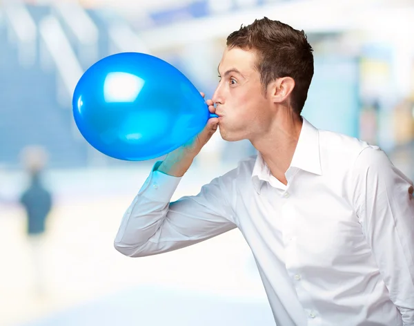 Porträtt av ung man blåser en ballong — Stockfoto