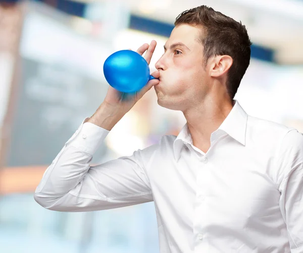 Portret van jonge man waait een ballon — Stockfoto