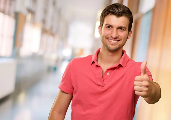 Giovane uomo sorridente con i pollici in su — Foto Stock