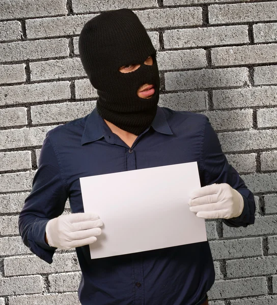 Uomo con una maschera da rapinatore che mostra una carta bianca — Foto Stock