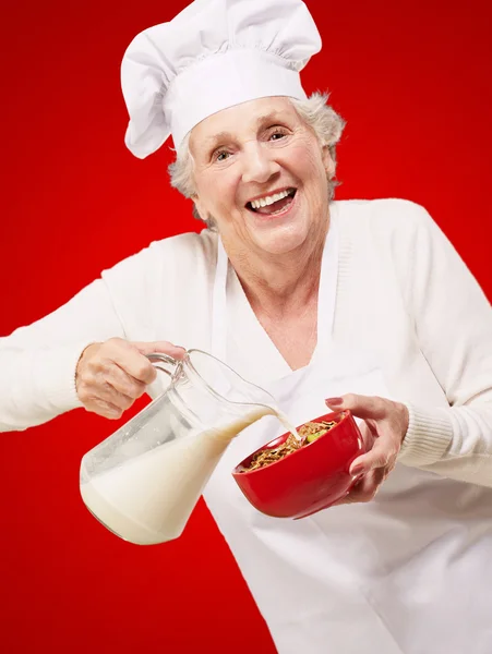 Seniorin gießt Milch ein — Stockfoto