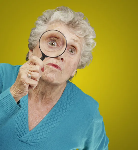 Retrato de una mujer mayor mirando a través de una lupa — Foto de Stock