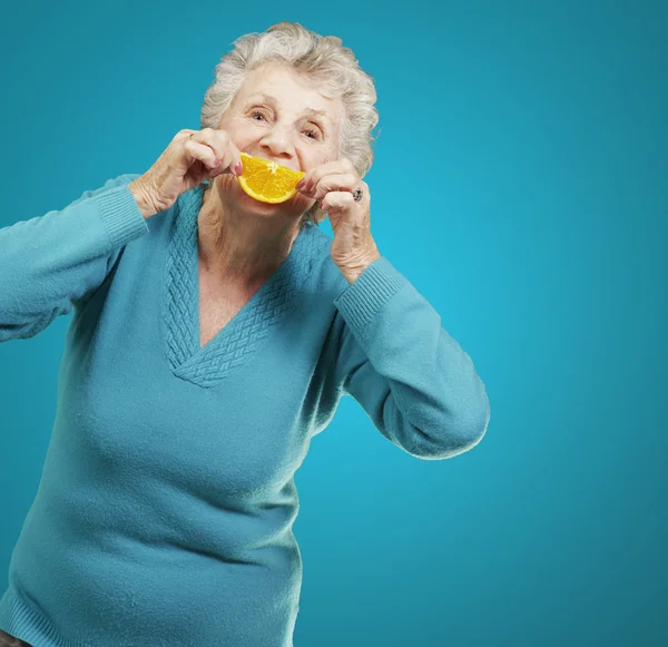 Porträt einer Seniorin, die eine Orangenscheibe vor sich hält — Stockfoto