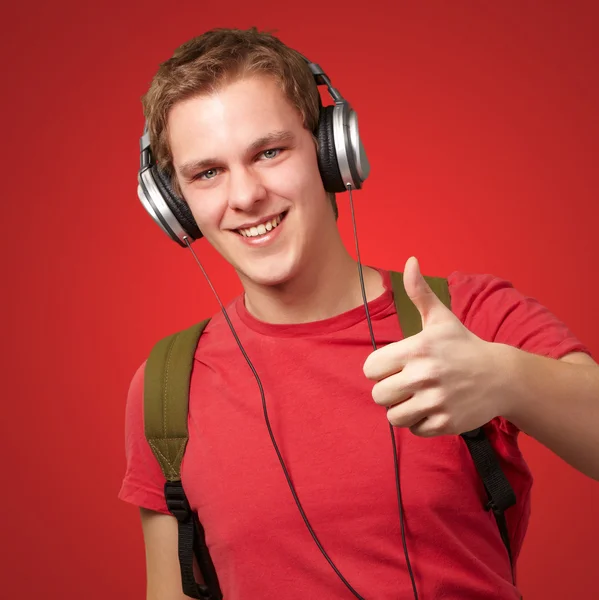 Retrato de un joven estudiante alegre escuchando música y gestos — Foto de Stock