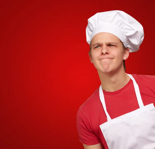 Junger Koch hat eine Idee über rotem Hintergrund — Stockfoto