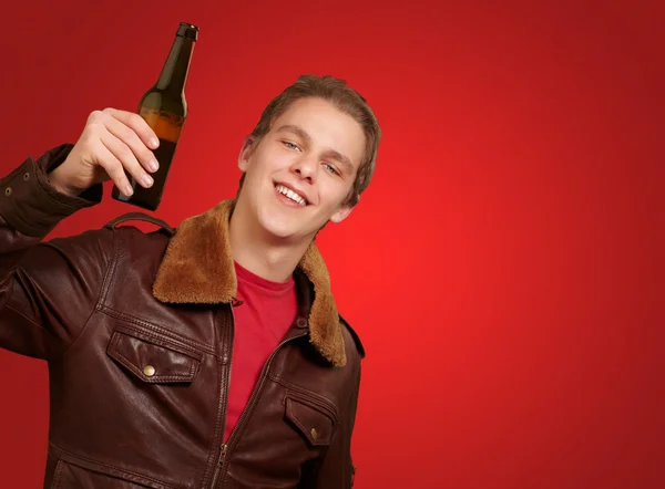 Portrait of young man holding beer on red background — Stock Photo, Image