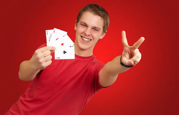 Retrato del joven haciendo un gesto de victoria jugando al póquer —  Fotos de Stock