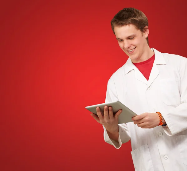 Retrato de un joven académico sosteniendo una tableta digital sobre rojo bac — Foto de Stock