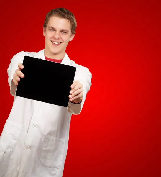 Portrét mladého muže, ukazující digitálním tabletu na červeném pozadí — Stock fotografie
