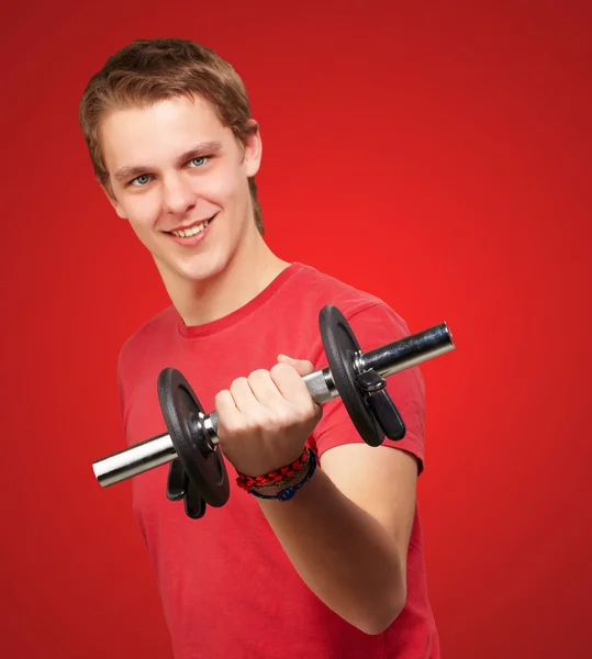 Retrato de jovem com pesos sobre fundo vermelho — Fotografia de Stock