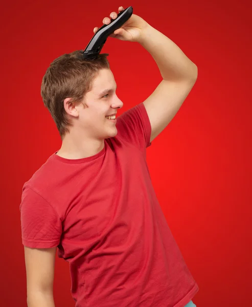 Retrato de jovem cortando o cabelo sobre fundo vermelho — Fotografia de Stock