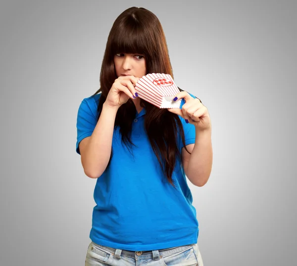 Girl looking through empty popcorn packet — Stock Photo, Image