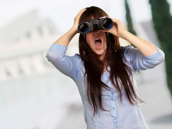 Porträt einer jungen Frau, die durch ein Fernglas blickt — Stockfoto