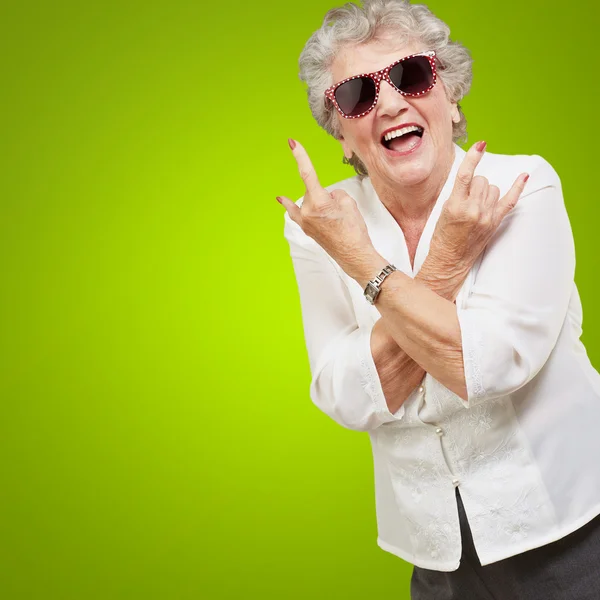 Seniorin mit Sonnenbrille macht flippige Aktion Stockbild