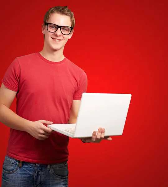 Portrait of young student man holding laptop over red background Royalty Free Stock Images