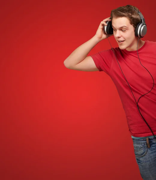 Portrait of young man listening music on red background Stock Photo