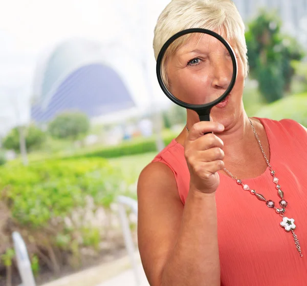 Mujer mayor mirando a través de una lupa — Foto de Stock